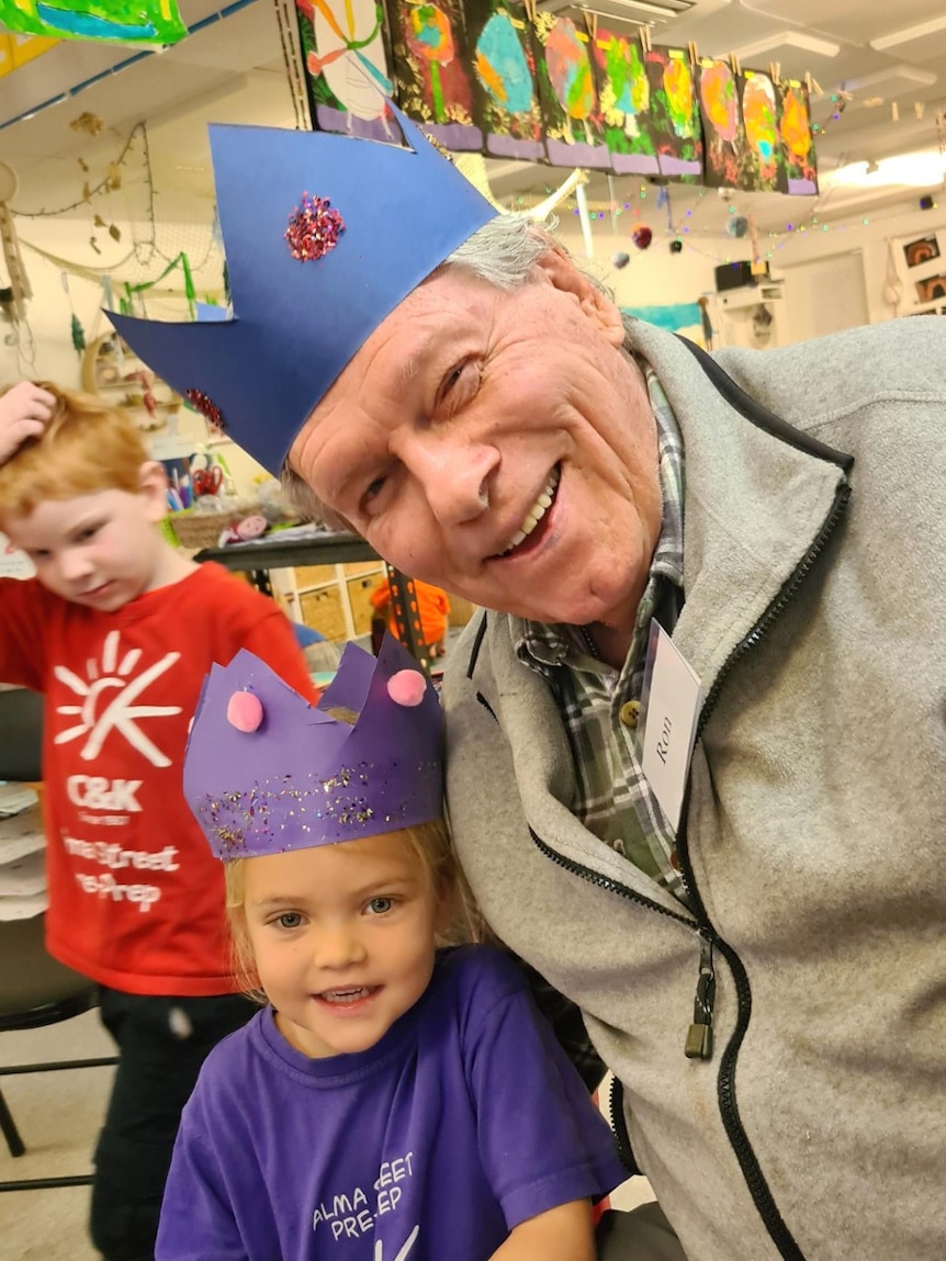 Male senior and young child wear party hats, smiling