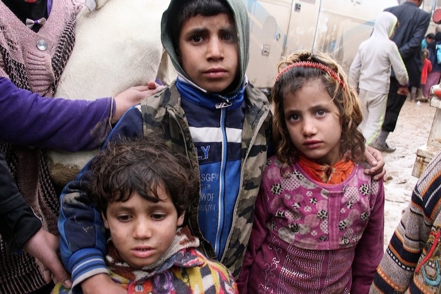 Three children, on the verge of tears and holding each other close, in the Hammam Al Alil camp south of Mosul.