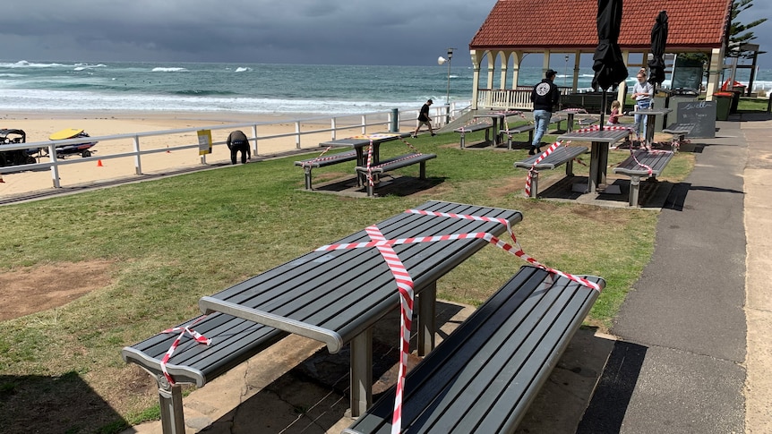 A bench near the beach that has been taped off.