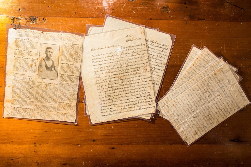 Three piles of brown paper - letters - sit on a brown wooden table.