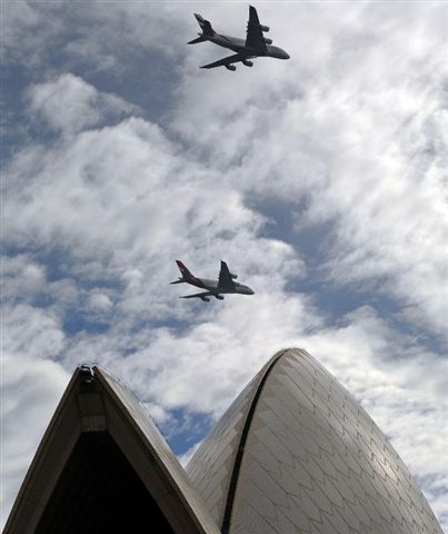 An Emirates A380 aircraft and a Qantas A380 aircraft fly above the Sydney Opera House.