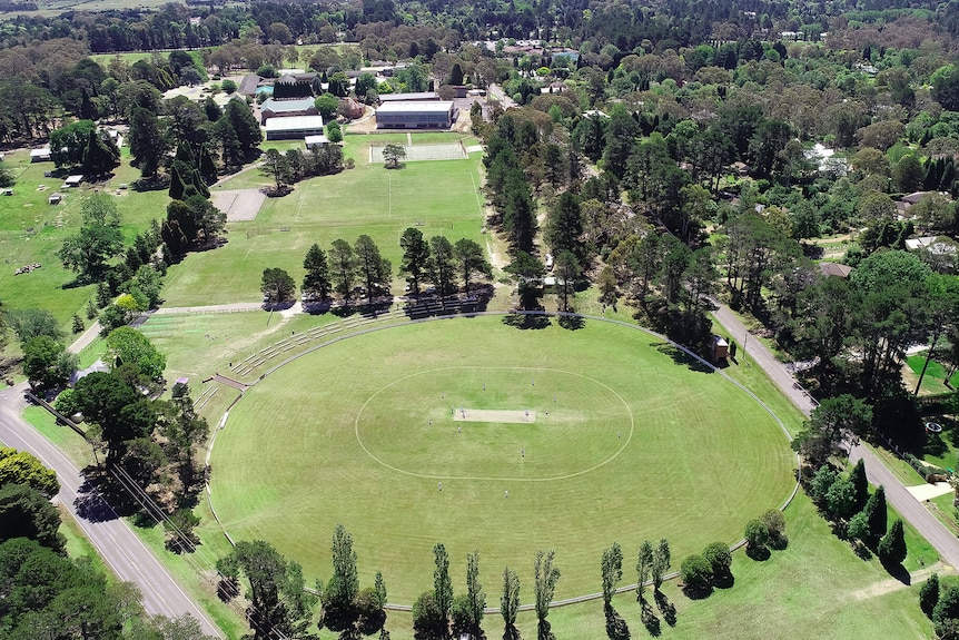 Green oval with trees and classroom buildings