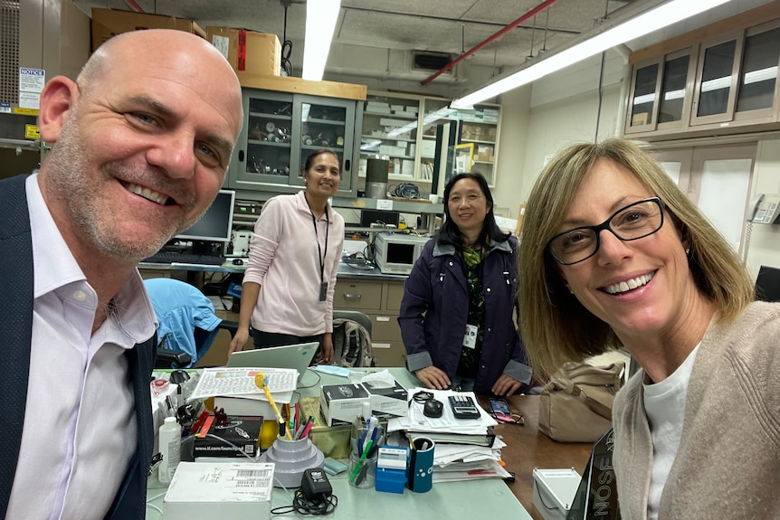 Four people in a lab smile for a selfie