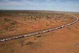 An aerial shot of a long queue of campervans on an outback road.
