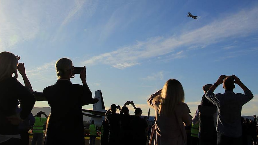 People take photos of Qantas 747 VH-OEJ as it flies over Shellharbour Airport.