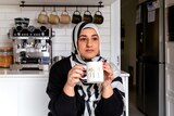 Food creator Lina Jebeile of The Lebanese Plate having a hot drink in her kitchen to unwind, her mug says 'Mum fuel'.
