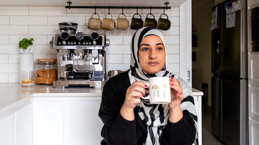 Food creator Lina Jebeile of The Lebanese Plate having a hot drink in her kitchen to unwind, her mug says 'Mum fuel'.