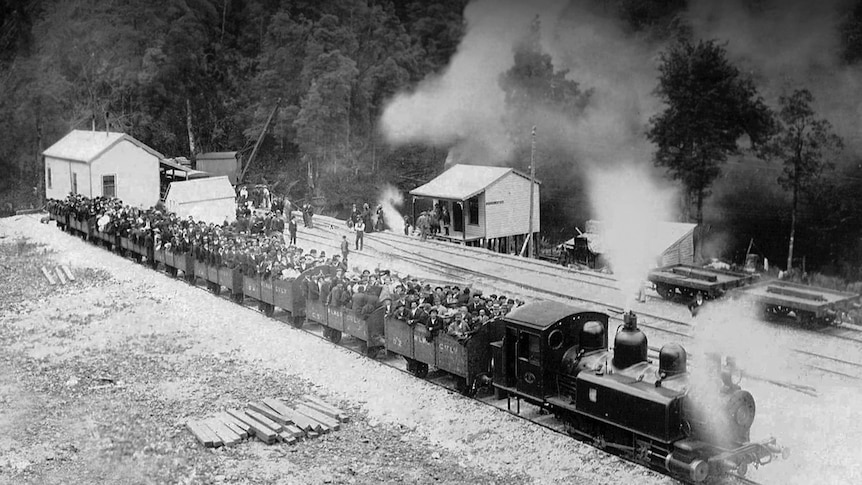 An historic image of train and ore wagons jam packed with people