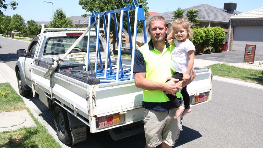Jack Gray holds his daughter Scarlett in front of a ute.