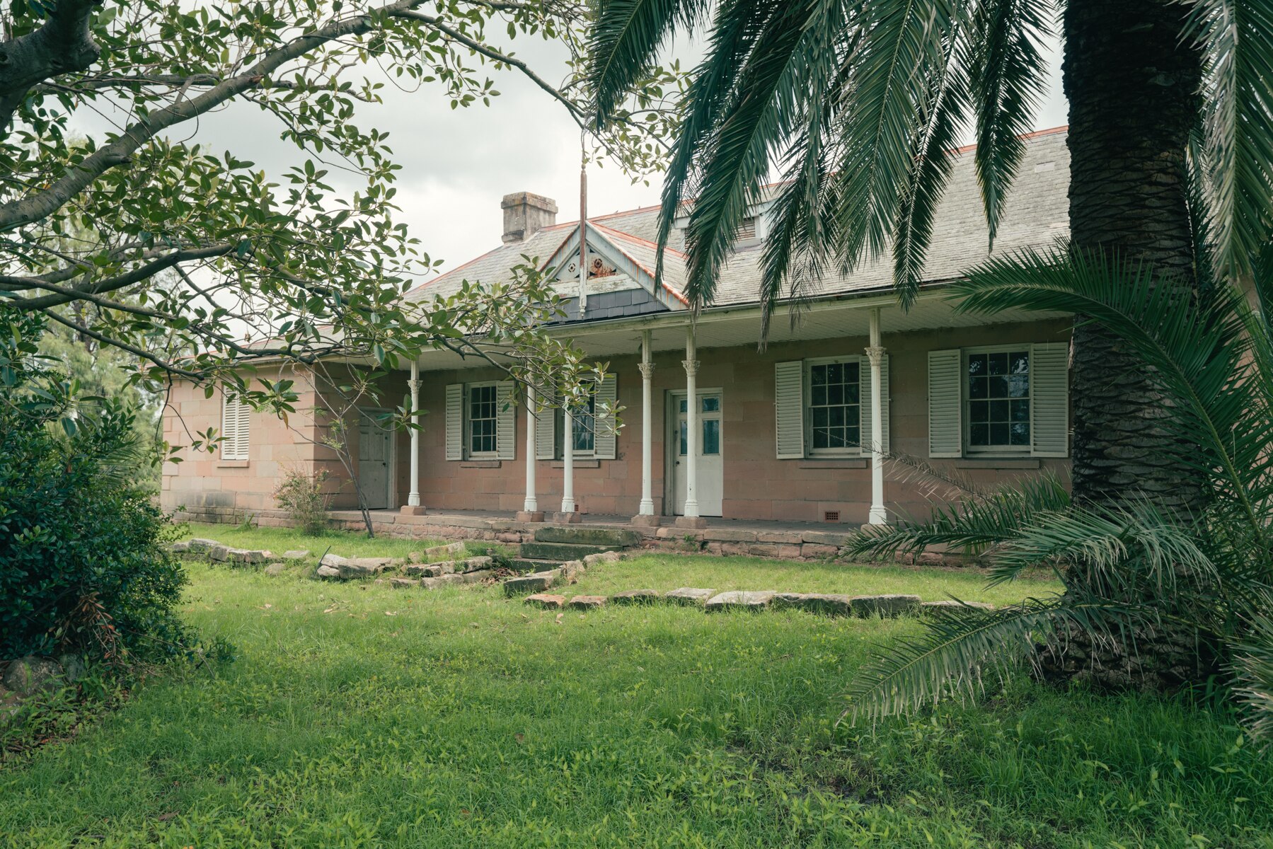 Grass leading up to a house with four windows and a door at the front
