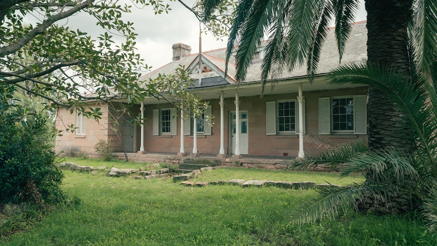 Grass leading up to a house with four windows and a door at the front