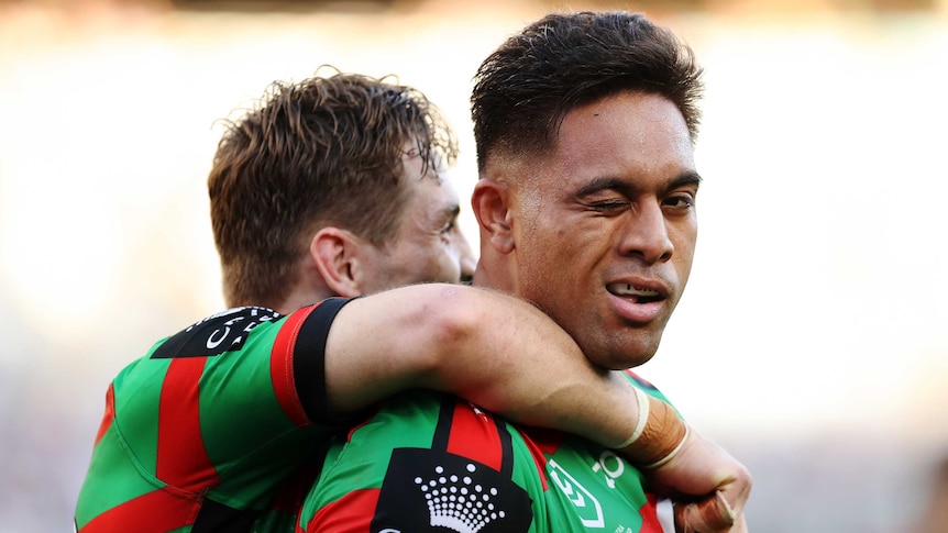 Tevita Tatola winks to the camera with a teammate hanging off his back