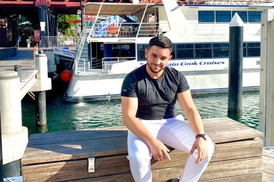 A man sitting in front of a sailing boat.