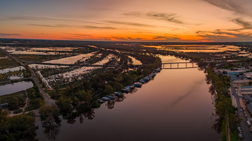 A wide sweeping river with an orange sunset