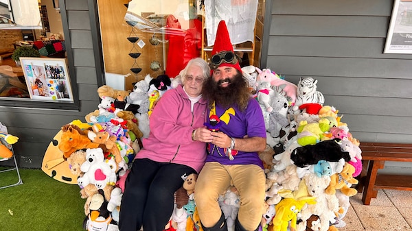 Costa the Gnome sitting with a lady on a couch covered with soft toys.