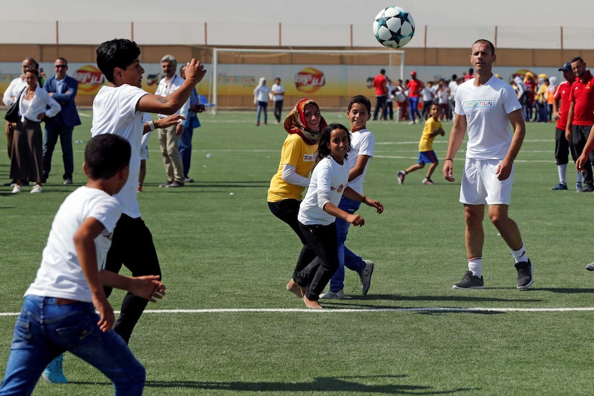 UEFA president Aleksander Ceferin plays football with refugees