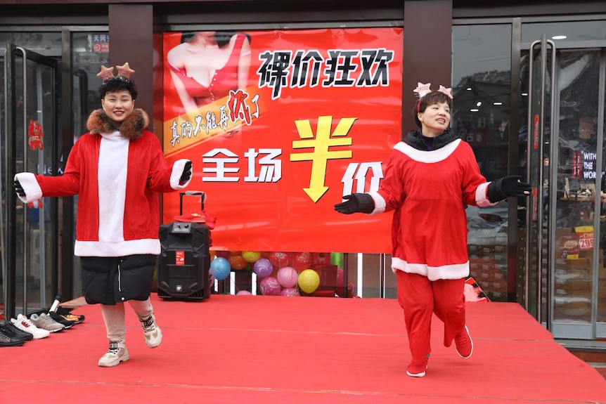 A sales staff from an apparel shop dance wearing Christmas themed costumes to promote a year-end sale.