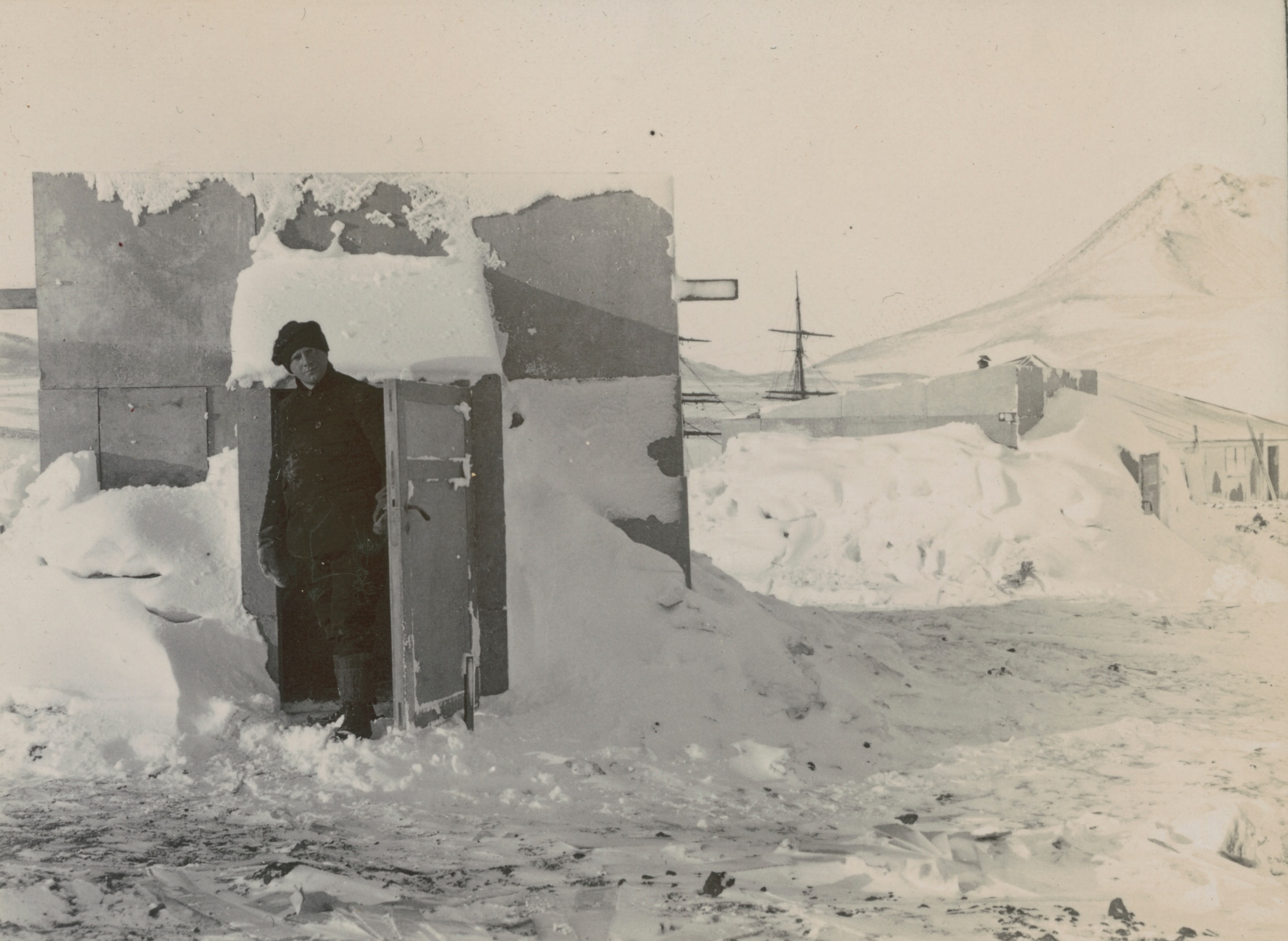 Australian physicist Louis Bernacchi stands in a doorway surrounded by ice on Antarctica