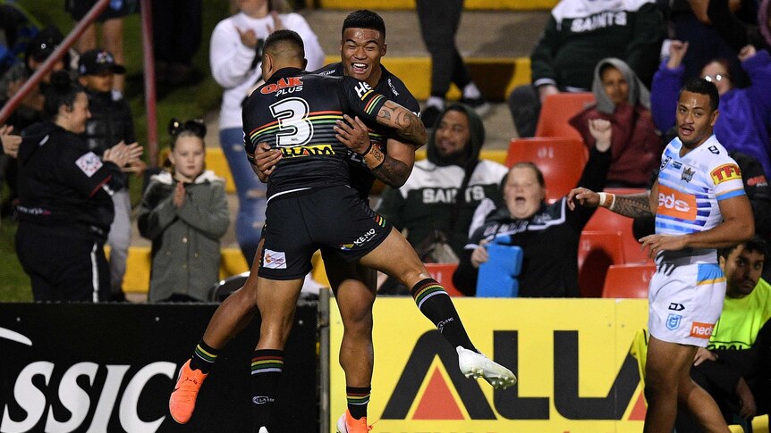 Brian Too and Dean Whare hug while leaping in the air. In the background, Panthers fans celebrate.