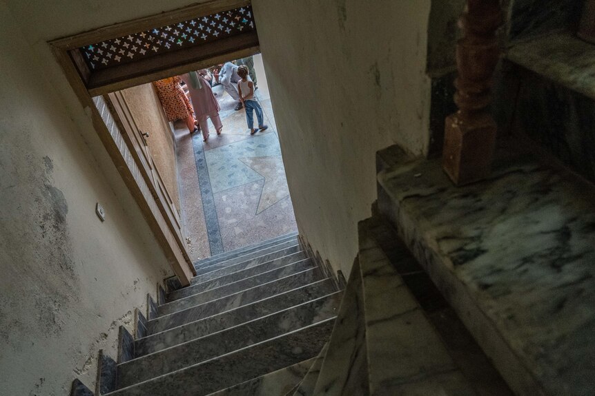 Taken from inside a stairwell, the image shows the feet of people outside through an open door. 