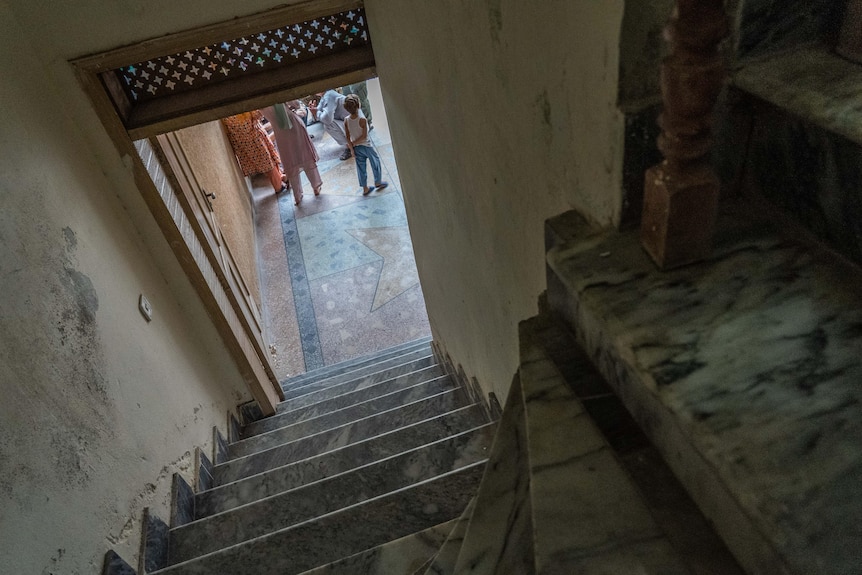 Taken from inside a stairwell, the image shows the feet of people outside through an open door. 