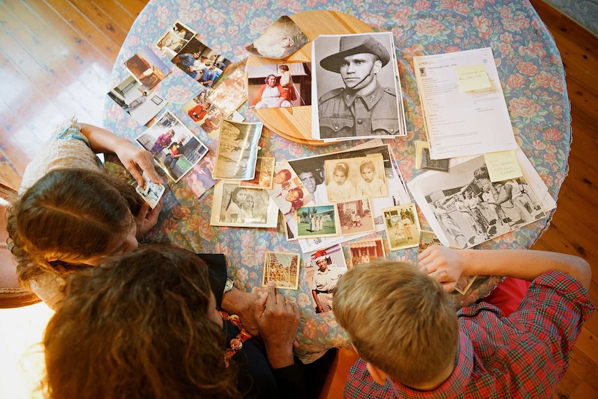 Old family photos are scattered across a table.