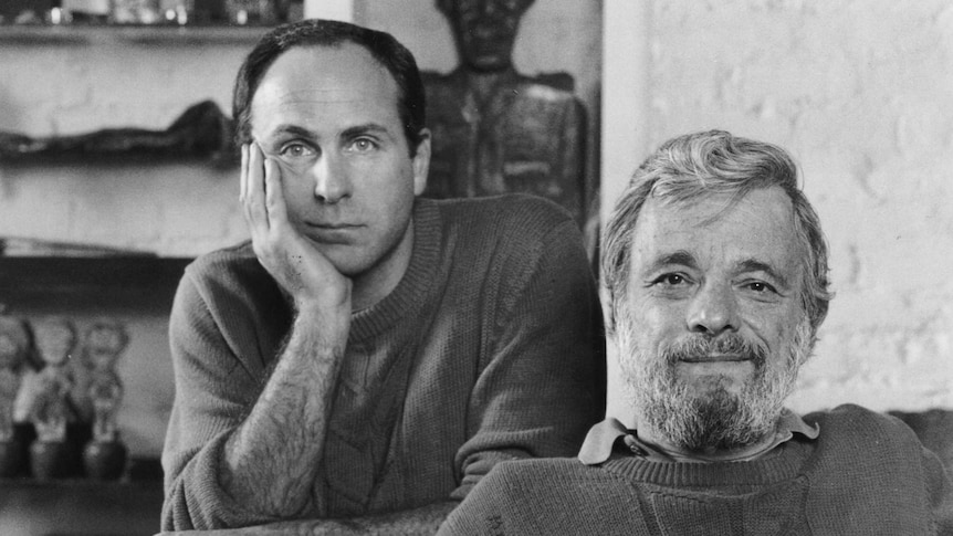 Stephen Sondheim sits on a couch with James Lapine leaning on the couch from behind.