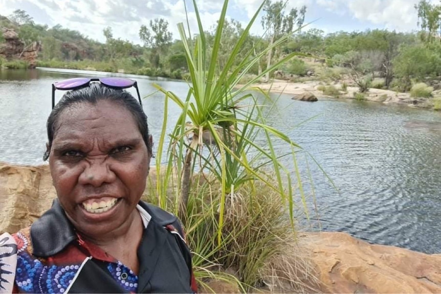 A woman smiling at the camera in front of a river