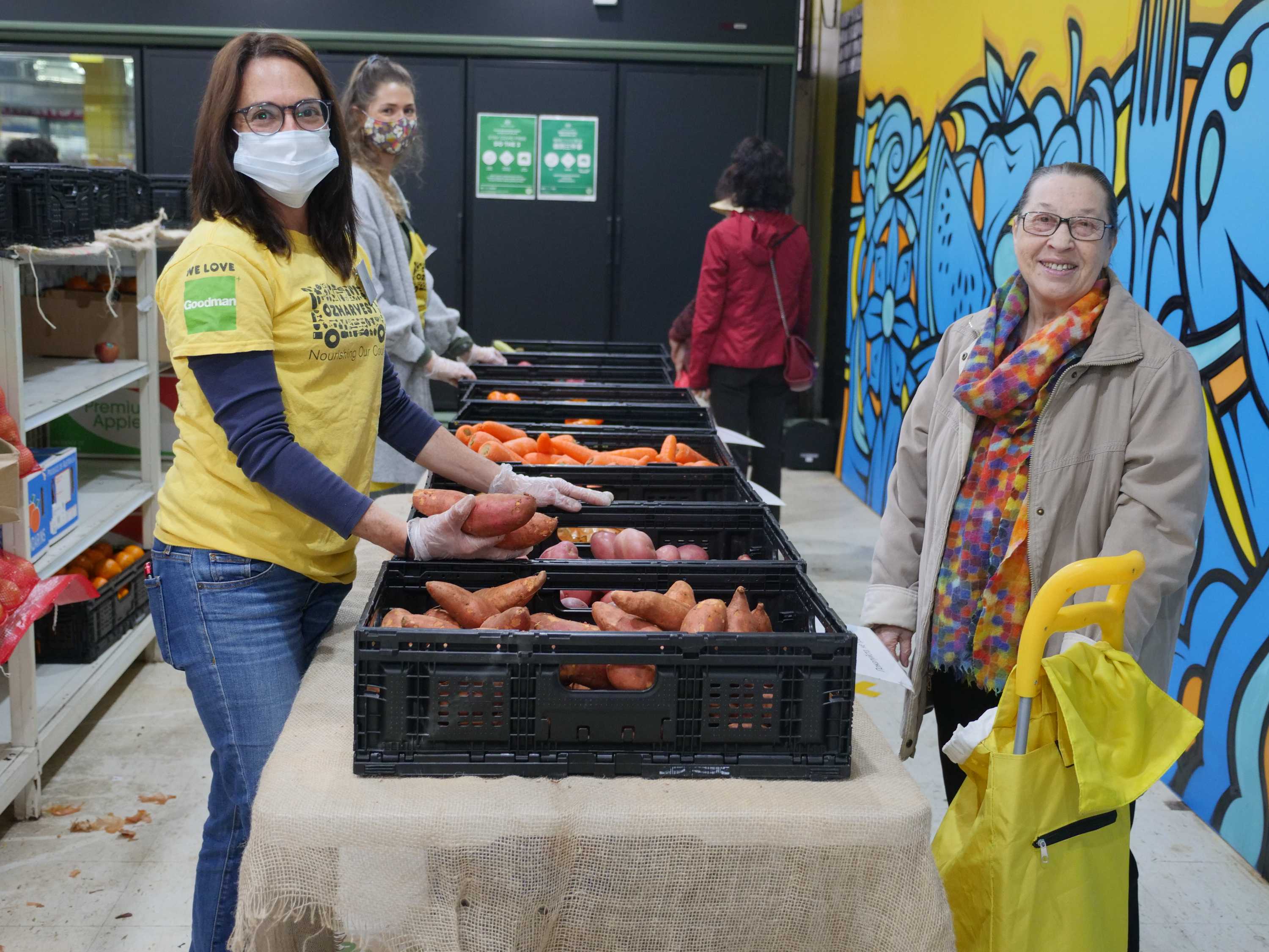 An OzHarvest worker stands with a customer at the Waterloo market, 2020.