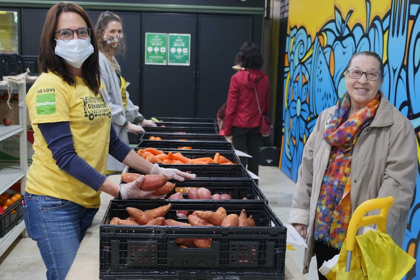 An OzHarvest worker stands with a customer at the Waterloo market, 2020.