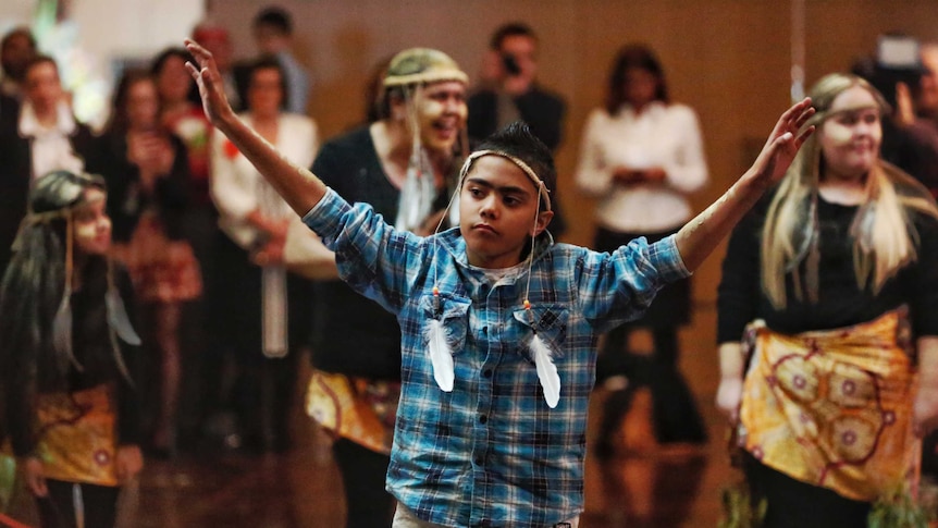 Young indigenous boy raises his arms to welcome the politicians to parliament.