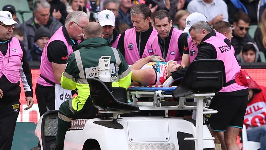 Port Adelaide's Robbie Gray is taken off the MCG after being knocked out in a tackle.