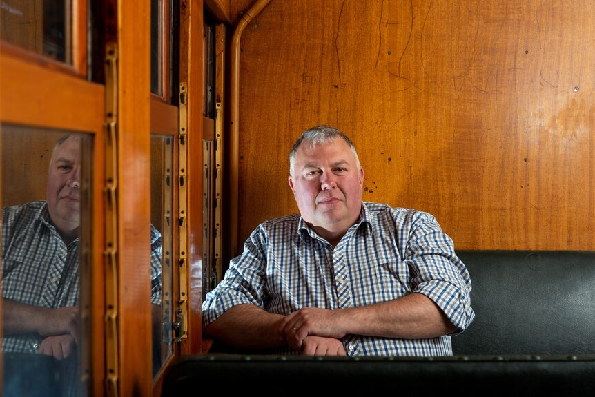 a middle-aged man sits in an old train carriage