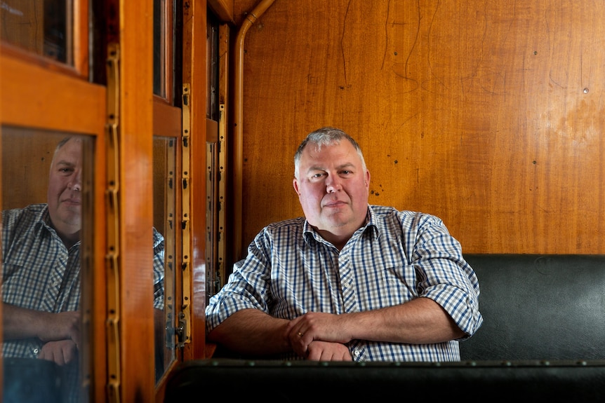 a middle-aged man sits in an old train carriage