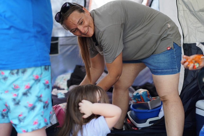 A smiling woman named Kristine Meakins bends down while talking to a child.