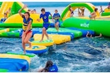 Kids playing on an inflatable water park.