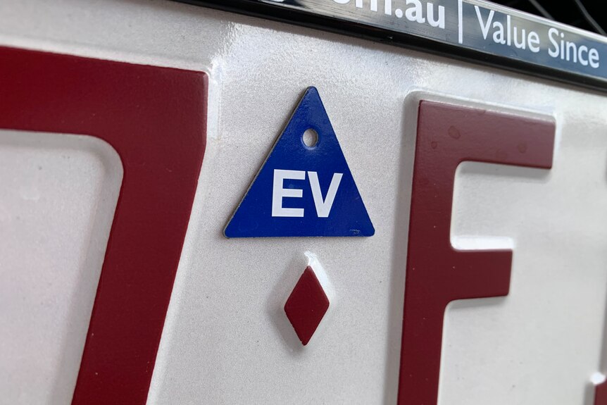 A close up of a Queensland number plate, showing a blue EV triangle used to mark electric vehicles