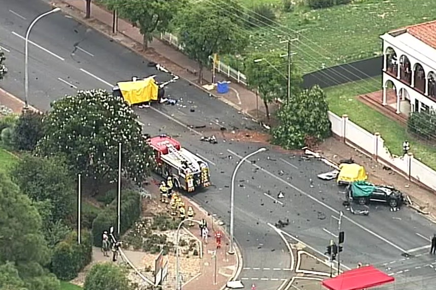 A birds-eye view of a crash scene involving three cars. Debris can be seen strewn across the road.