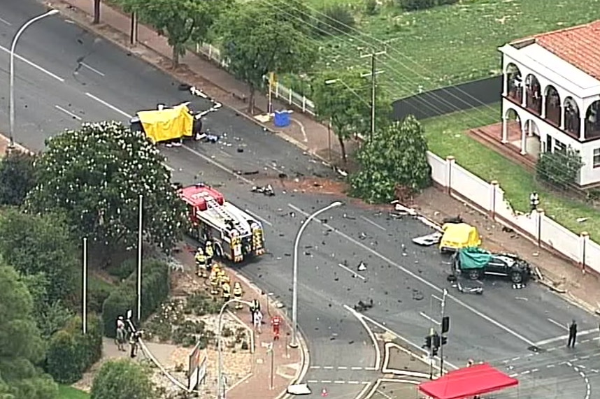 An aerial shot of a crash scene involving three cars. Debris is strewn across the road.
