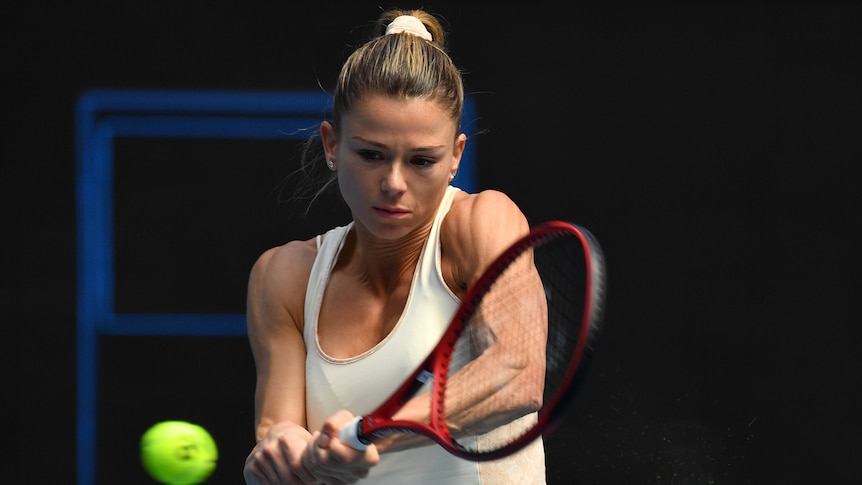 Camila Giorgi prepares to hit a tennis ball mid-air on the court.