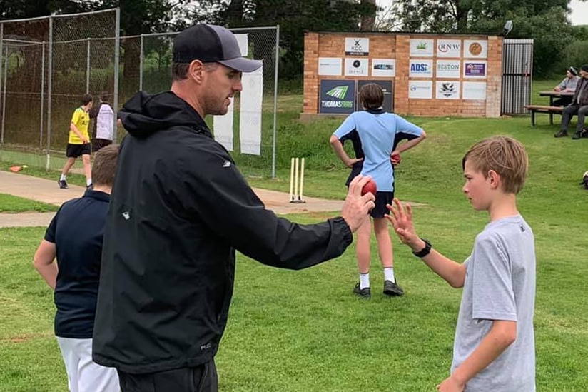 Shaun Tait shows a young cricketer how to hold a ball.