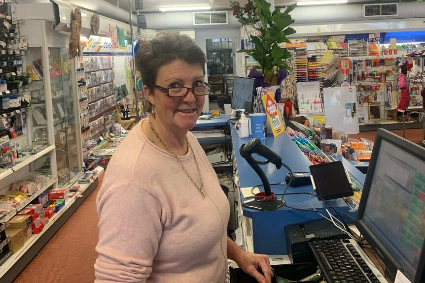 woman standing at counter of a newsagency 