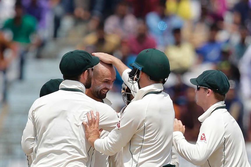 Teammates surround Nathan Lyon to congratulate the spinner on taking a wicket.