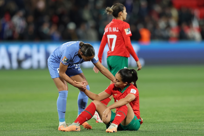 Estelle Cascarino of France helps Sakina Ouzraoui of Morocco off the ground at the FIFA Women's World Cup.