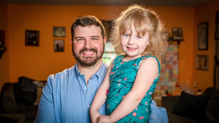 A man holds a smiling young girl in his arms