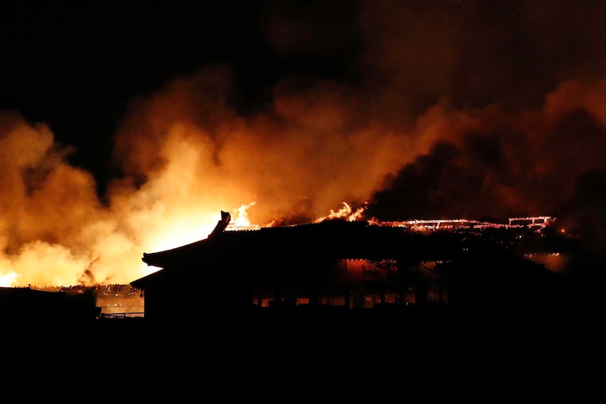 At night, the entire Shuri castle is on fire, bright orange flames glow in the night