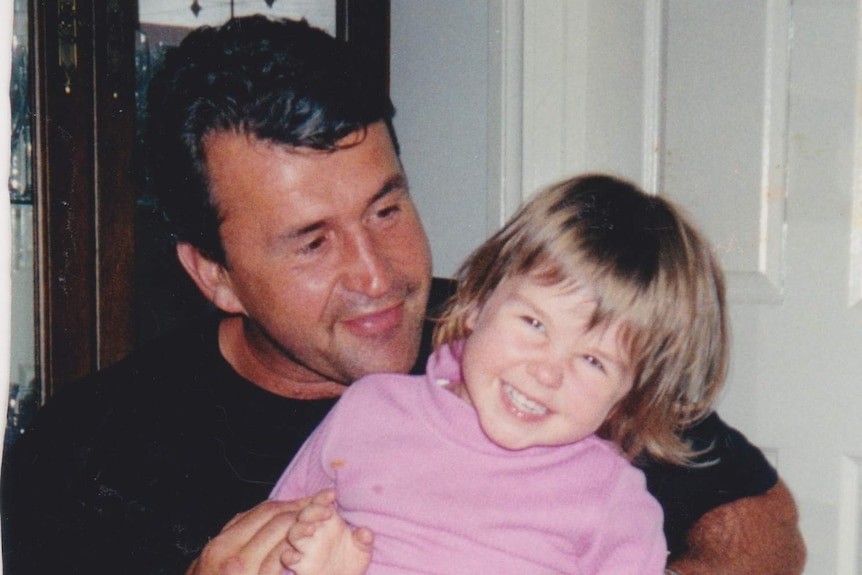 A little girl giggles while sitting on her father's lap.