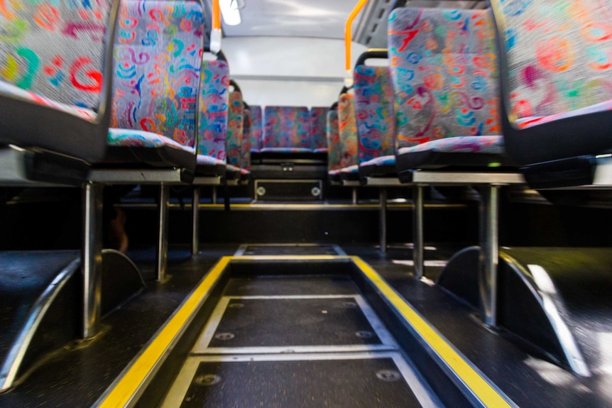 Looking up at the seats on a bus from the centre aisle.