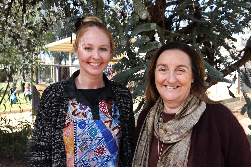 Two women standing under a tree.