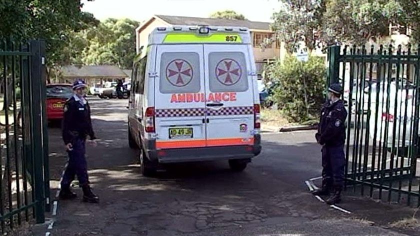 Police stand outside the Merrylands High School in Sydney as an ambulance enters